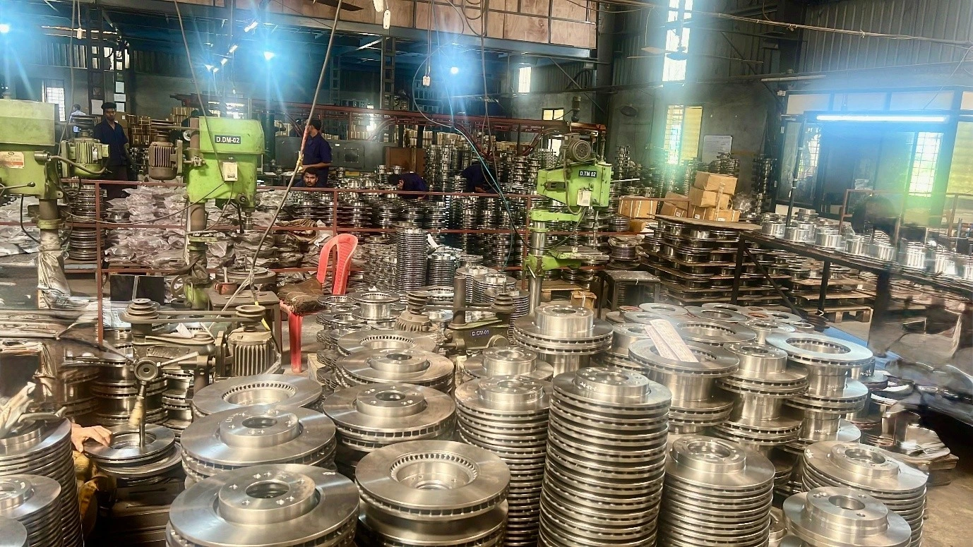 Stacks of ductile iron and grey iron brake rotor castings on the floor of a VIA INDIGOS partner foundry in India after fettling and shot blast, ASTM A536 and ASTM A48 grades ready for CNC machining, dimensional inspection and dispatch to US automotive aftermarket and heavy duty buyers