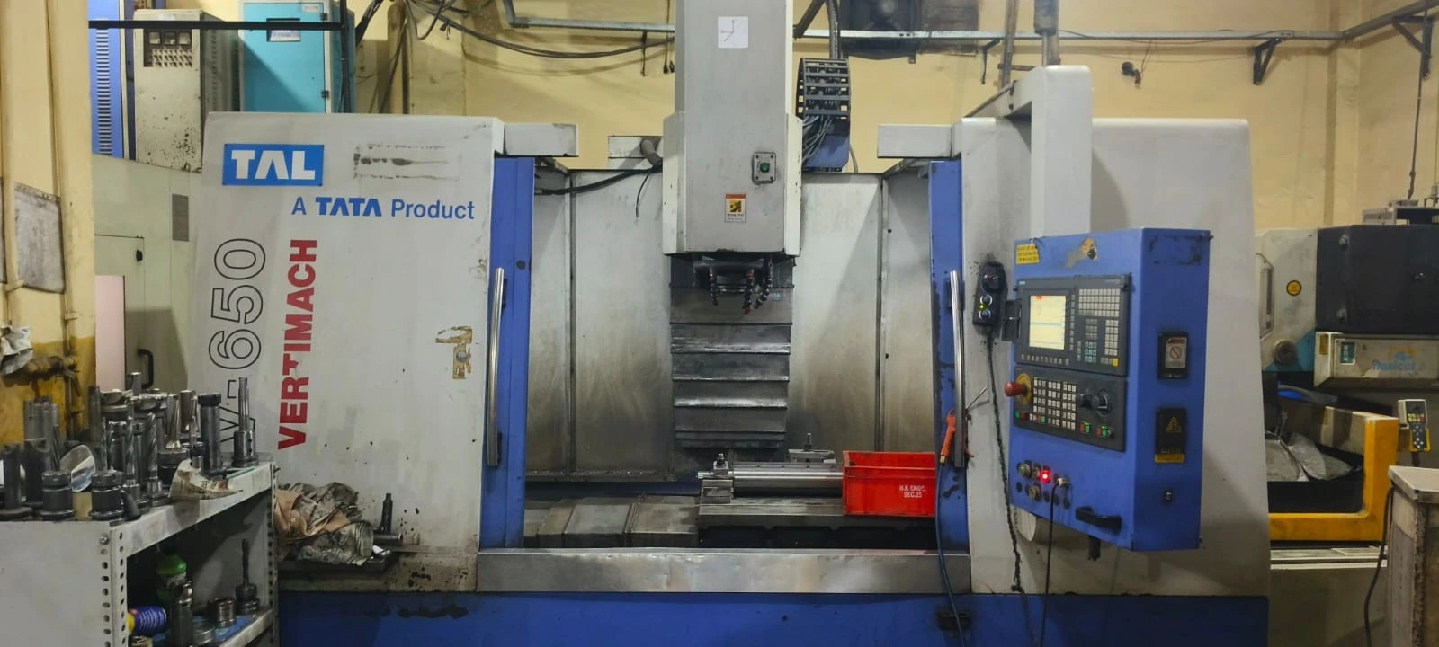 3-axis CNC vertical machining center milling an aluminium housing at a VIA INDIGOS partner facility in India, fixture clamped on the table