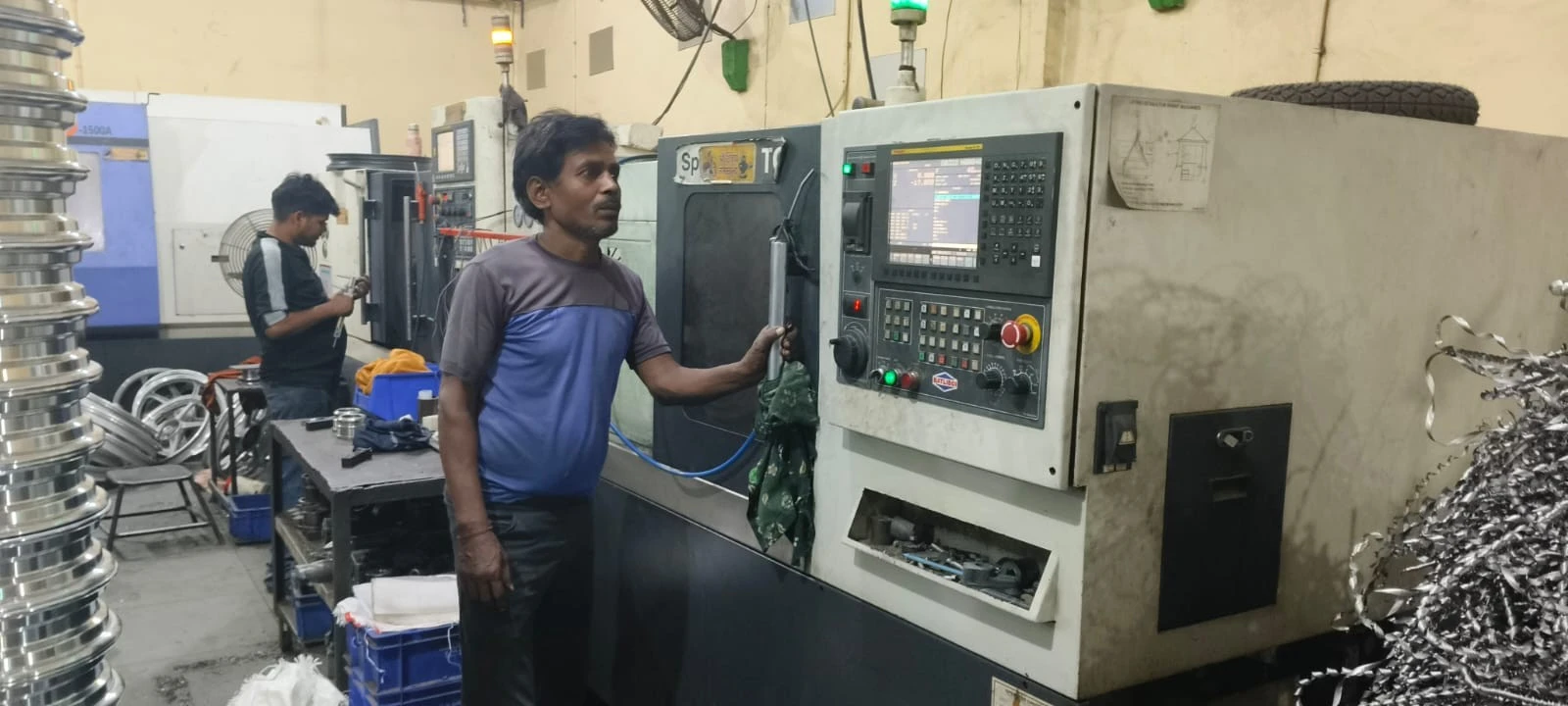 Two operators at a CNC milling center at our Pune partner facility, checking a fixture setup before the first cut on a new program