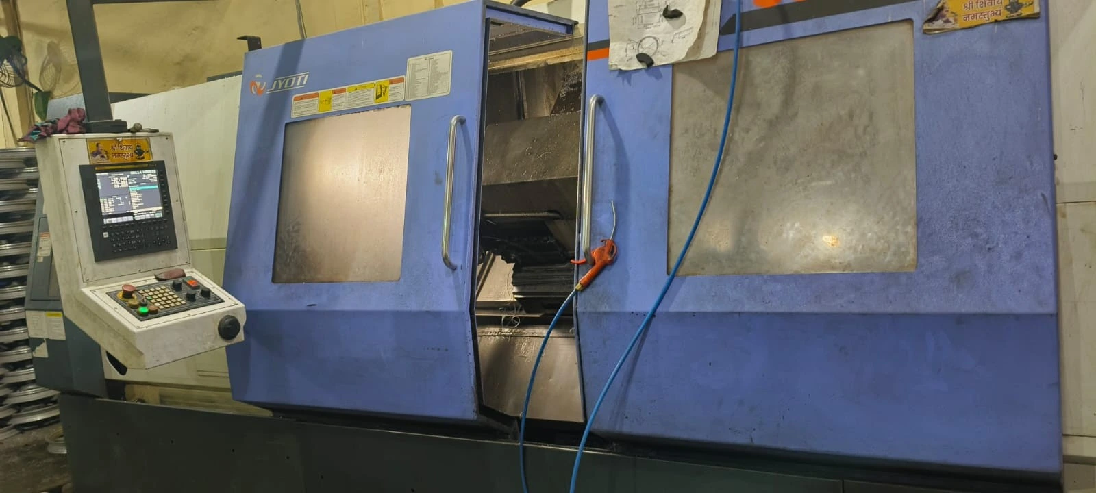 CNC turning center cutting a steel shaft at a VIA INDIGOS partner facility in India, live tooling engaged during a production run