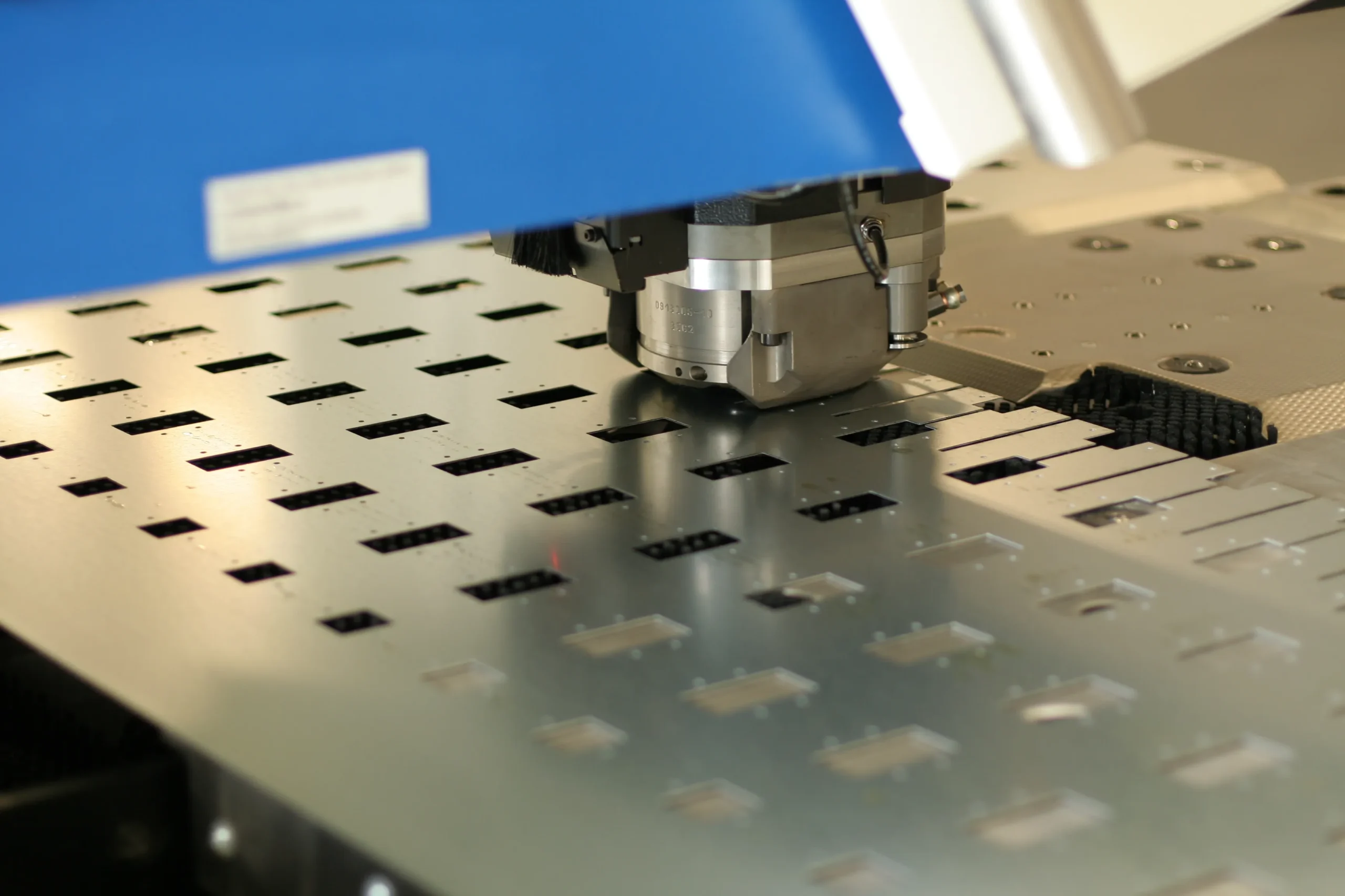 CNC turret punching holes and cutouts in a steel sheet at our India partner facility