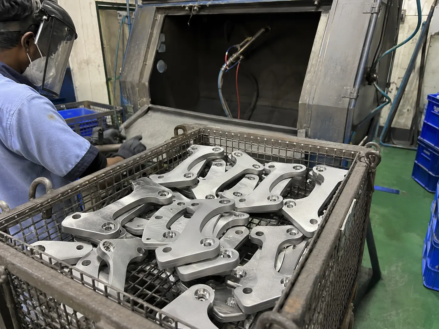 Caliper mounting brackets being sand blasted before plating in India
