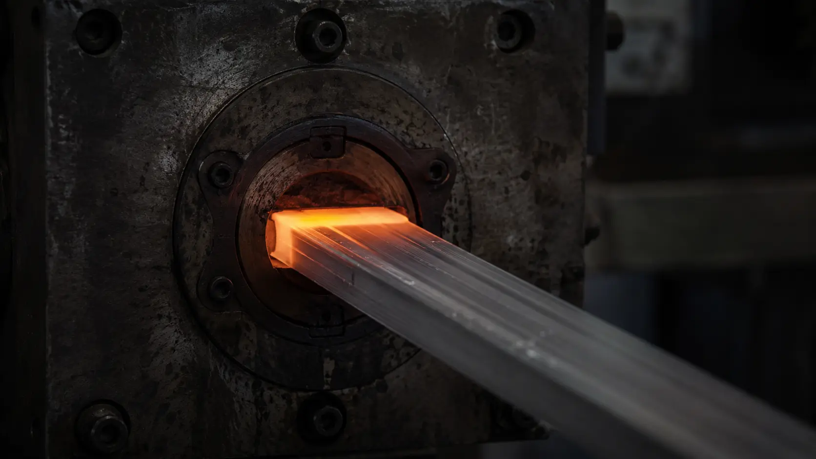 Hot 6063 aluminum profile leaving the extrusion die still glowing at a partner extrusion facility in India