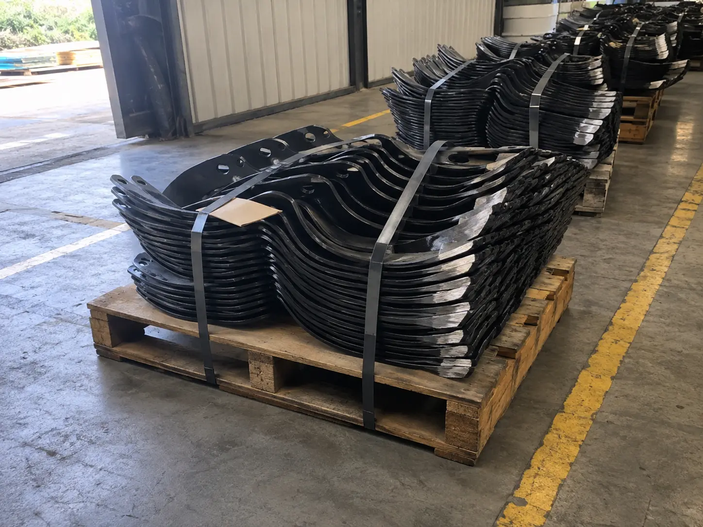 Forged boron steel rotary tiller blades strapped in nested bundles on pallets before export at a VIA INDIGOS partner plant in India